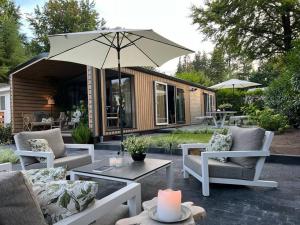 een patio met stoelen en een tafel met een parasol bij Luxe vakantiehuis “Saalien” in Beekbergen