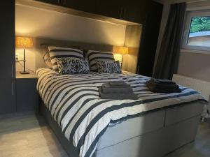 a bedroom with a large bed with striped sheets and pillows at Luxe vakantiehuis “Saalien” in Beekbergen