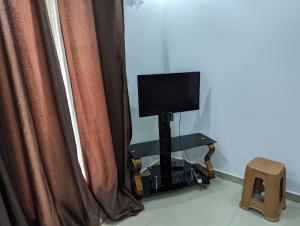 a television sitting on a stand in front of curtains at MBAO Sipres Appartement moderne bord de mer in Mbaw +12 photos