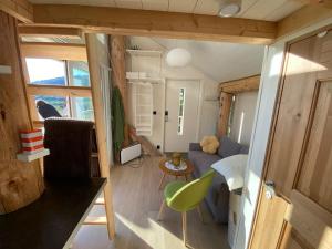 a small living room with a green chair in a tiny house at Minihus med drømmeutsikt til Sunnmørsalpene in Aure