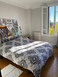 Schlafzimmer mit einem Bett mit einer schwarzen und weißen Bettdecke in der Unterkunft L'ermitage in Agen