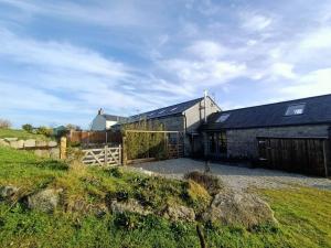 a large black building with a fence and a field at Treverrows Barn - Barn Conversion on the Farm in Penryn