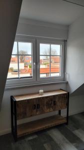 einen Holztisch in einem Zimmer mit zwei Fenstern in der Unterkunft Apartment "The Loft" in Heiligenhafen in Heiligenhafen