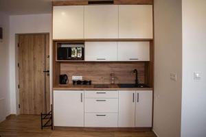a kitchen with white cabinets and a sink at Place4You in Ostróda