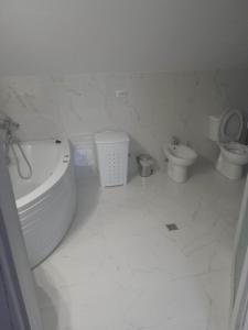 bagno bianco con vasca e servizi igienici di Izabella Guest House a Săcele