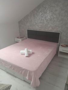 Una cama rosa con una toalla encima. en Izabella Guest House, en Săcele