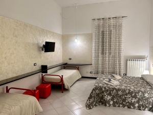 a room with two beds and a table and a tv at Ohana by Casimiro in Trapani
