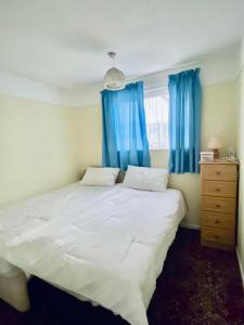 a bedroom with a large bed with blue curtains at Quiet and Comfy 2- bedroom Holiday Chalet, walk to the beach, Norfolk in Great Yarmouth