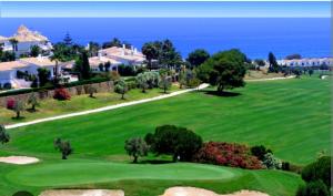 um campo de golfe com o oceano ao fundo em APARTAMENTOS LOS HIDALGO GOLF em Manilva