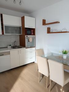 KlisにあるApartman ANAMARIAの白いキャビネット、テーブルと椅子付きのキッチンが備わります。