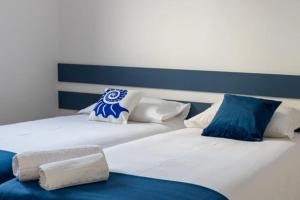 two white beds with blue and white pillows at Perto do Mar, Alojamento Local - Espaço T2 privativo in Vagos