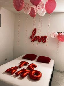 ein Bett mit roten Ballons und ein Liebesschild drauf in der Unterkunft BARU ESTELAR in Medellín