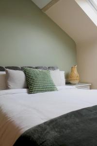 a bedroom with a large white bed with green pillows at Charming 1-Bed loft in Caerleon in Newport