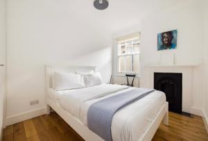 a white bedroom with a bed and a fireplace at Cool, Quiet Notting Hill 2 BED APT in London