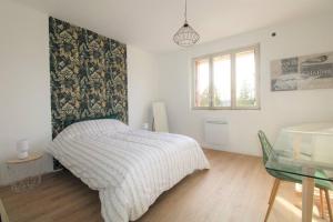 Schlafzimmer mit einem Bett, einem Tisch und einem Fenster in der Unterkunft Joli appartement au calme in Lay-Saint-Christophe