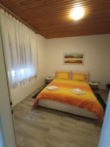 a bedroom with a bed with orange sheets and a window at Apartments Timi in Poreč