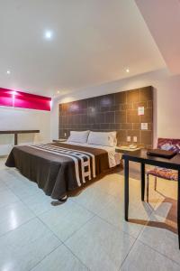 1 dormitorio con 1 cama grande y 1 mesa en First Inn Hotel & Business, en Texcoco de Mora