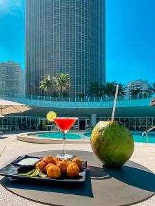 a plate of food and a drink and a melon at Hotel Nacional Vista Mar c/ Banheira in Rio de Janeiro