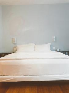 uma grande cama branca com lençóis e almofadas brancos em Pacific Blue Inn em Santa Cruz