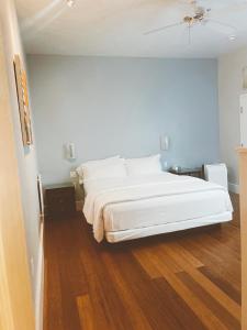 a bedroom with a white bed and a wooden floor at Pacific Blue Inn in Santa Cruz