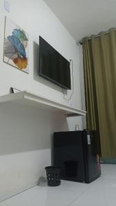 uma televisão de ecrã plano pendurada numa parede por cima de um frigorífico em Pousada Santo Amaro em Santo Amaro