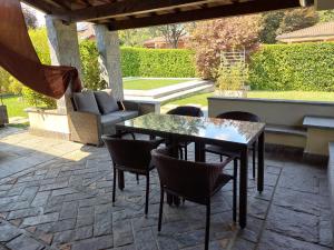 eine Terrasse mit einem Tisch, Stühlen und einem Sofa in der Unterkunft RESIDENZA BERETTA Como Lake -A- in Orsenigo