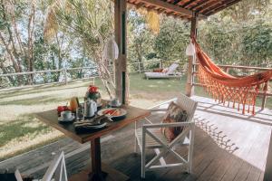 a table and chairs on a deck with a hammock at Madeiro Beach Hotel in Pipa