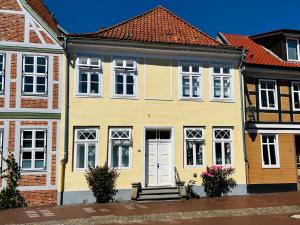 a yellow house with a white door at Das Stader Nest in Stade