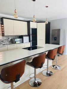 a kitchen with a white counter and brown bar stools at Home Away From Home in Johannesburg