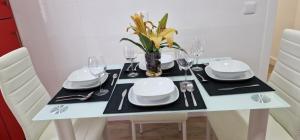 a dining table with white plates and glasses and a vase of flowers at Casa Roman LUX in León