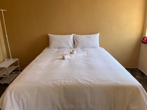 a large white bed with a white towel on it at Eldos Guest House in Soweto