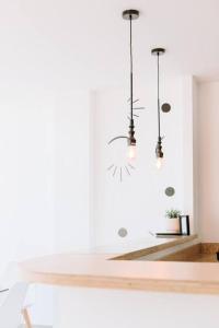 uma sala de jantar branca com duas luzes pendentes em O & D’s Gallery Apartment em San Salvador