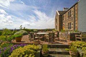 un patio con mesa y sillas frente a un edificio en Loch Gorm House, en Bruichladdich