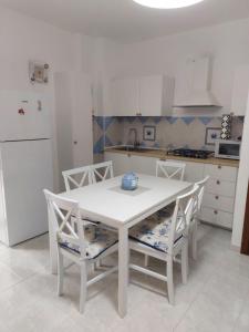 cocina con mesa blanca, sillas y nevera en Casa Alghero Lido, en Alghero