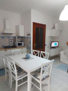 una cucina con tavolo e sedie bianchi in una stanza di Casa Alghero Lido ad Alghero