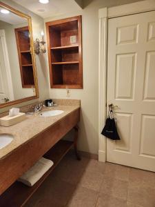 La salle de bains est pourvue de 2 lavabos, d'un miroir et d'une porte. dans l'établissement Best Western White House Inn, à Bangor