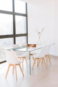ein Esszimmer mit einem Glastisch und weißen Stühlen in der Unterkunft O & D’s Gallery Apartment in San Salvador