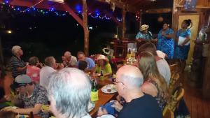 grupa ludzi siedzących przy stole na imprezie w obiekcie Aroa Beachside Resort w mieście Rarotonga