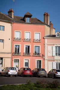 ein rosa Gebäude mit davor geparkten Autos in der Unterkunft Appartement luxueux 2 chambre CENTRE VILLE Langkawi in Chalon-sur-Saône
