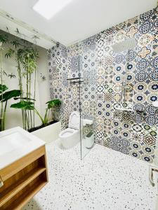 a bathroom with a toilet and a mosaic wall at Truc Home in Danang