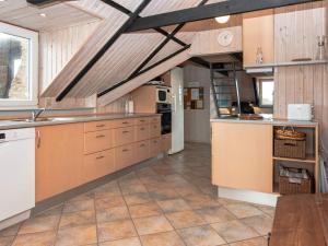 uma grande cozinha com armários de madeira e um tecto em 8 person holiday home in Ringk bing em Nørre Lyngvig
