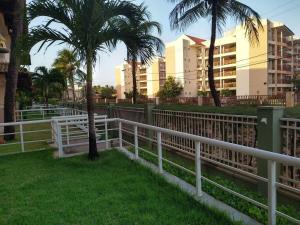 a white fence next to palm trees and buildings at Porto das Dunas paraíso 300m do Beach Park in Aquiraz