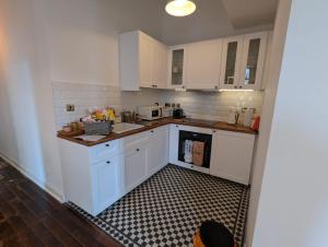 a kitchen with white cabinets and a black and white tile floor at Camberwell Church Street in London
