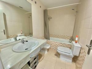 łazienka z umywalką, toaletą i lustrem w obiekcie Apartamento nuevo con piscina, temporada w mieście El Puerto de Santa María