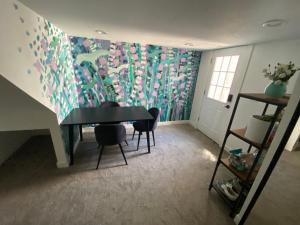een kamer met een tafel en stoelen en een muurschildering bij Artsy Platt Park Suite, Quick Mountain Access! in Denver