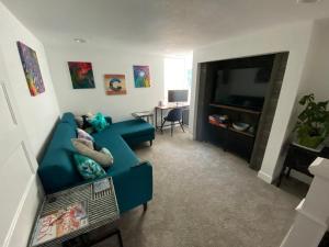 een woonkamer met een blauwe bank en een televisie bij Artsy Platt Park Suite, Quick Mountain Access! in Denver