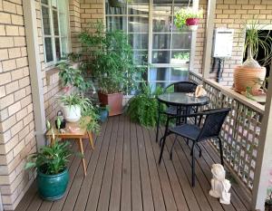 een veranda met een tafel en stoelen en potplanten bij Azalea Bed and Breakfast Hideaway in Tura Beach