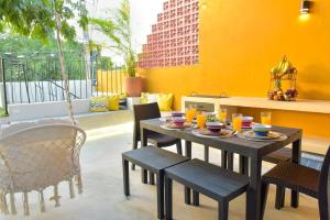 une table à manger, des chaises, une table et un mur jaune dans l'établissement K an nah Diseño tropical inspirado en el jaguar, à Mérida
