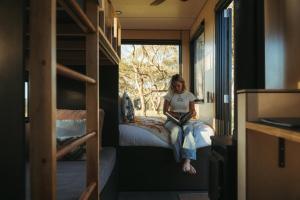 CABN Clare Valley في Mintaro: امرأة تجلس على سرير في غرفة