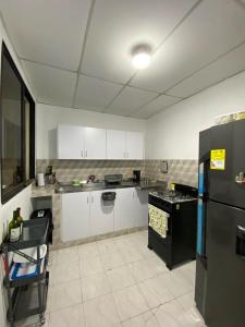 a kitchen with white cabinets and a black refrigerator at Habitaciones independientes cerca al aeropuerto 3 in Cartagena de Indias